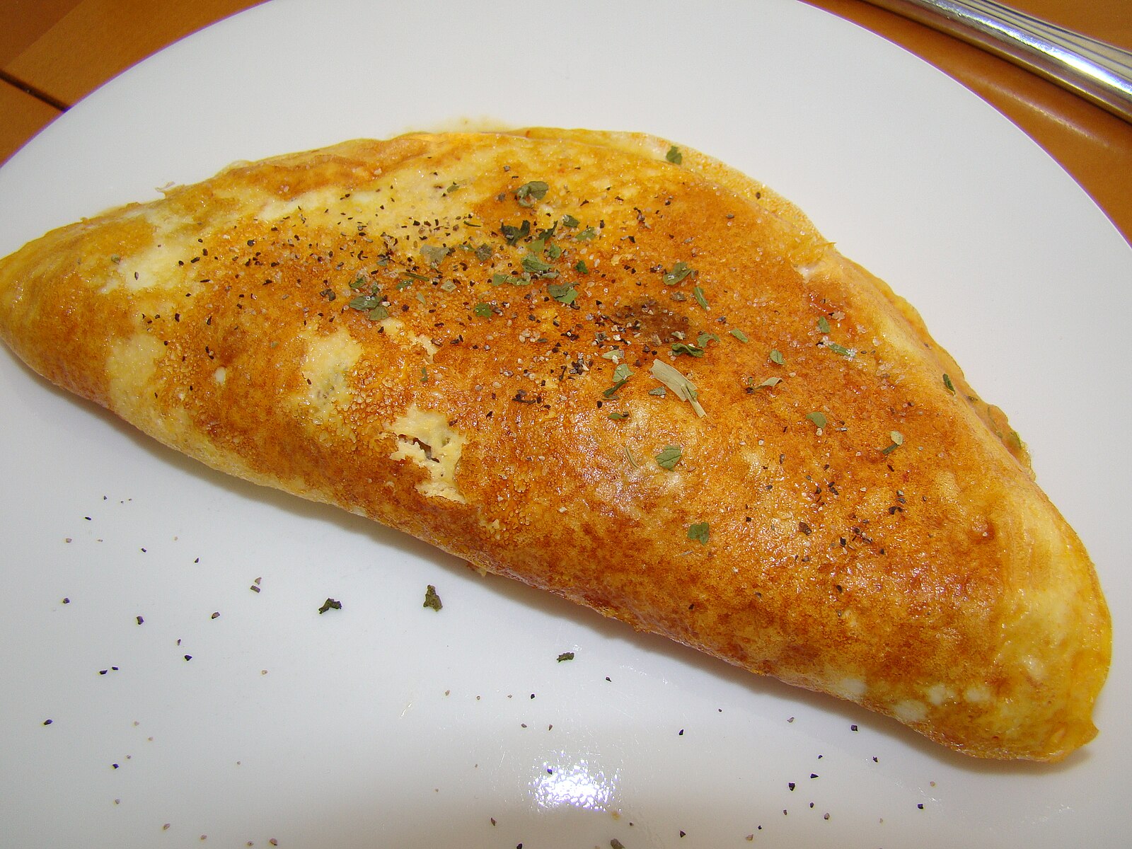 folded golden brown omelet on white plate